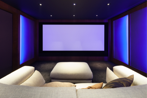 large couch space faced toward a large projector screen with blue lighting