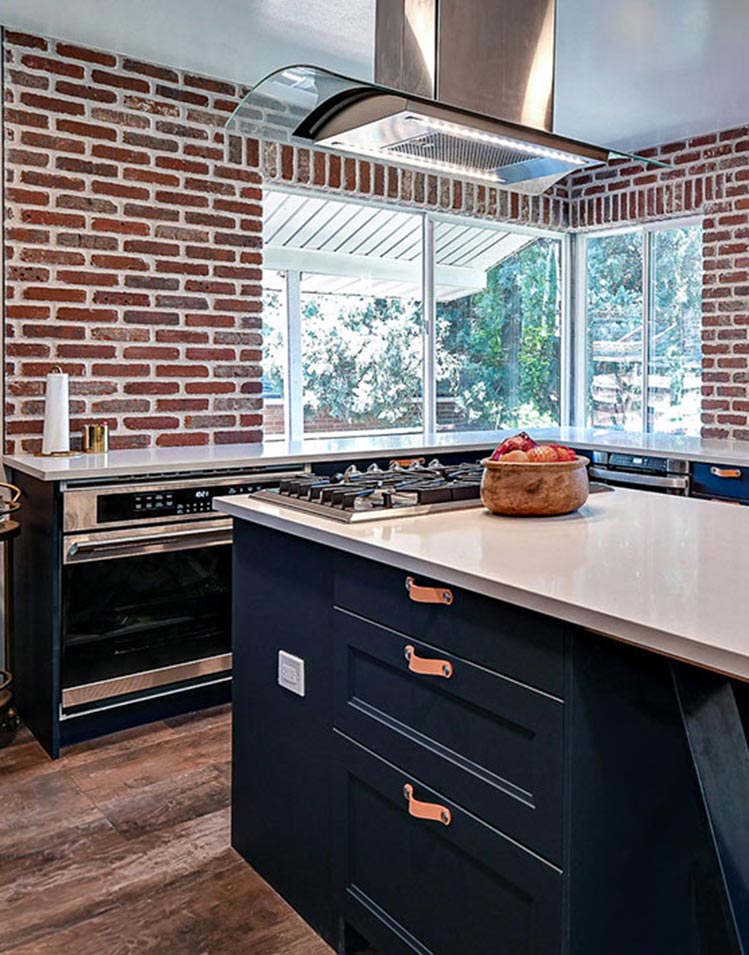 Remodeled kitchen with dark blue cupboards and red brick walls