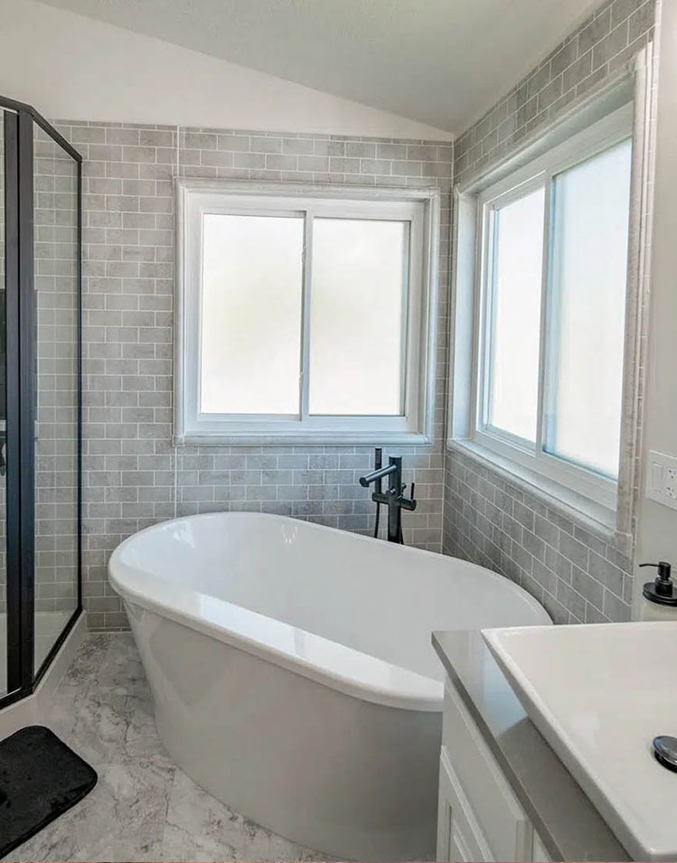 Modern bathroom with grey tile floors and walls and deep tub