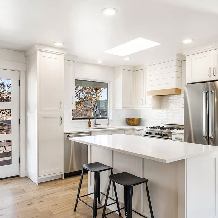 Bright white kitchen with island and door to backyard