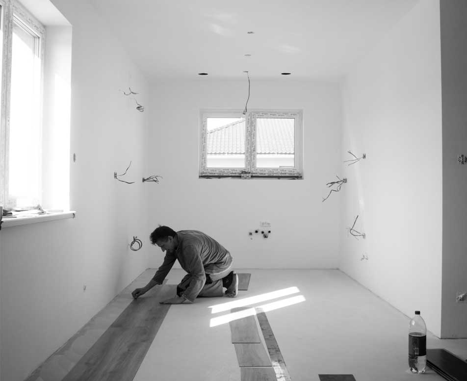 Man laying flooring down after completing foundation work.